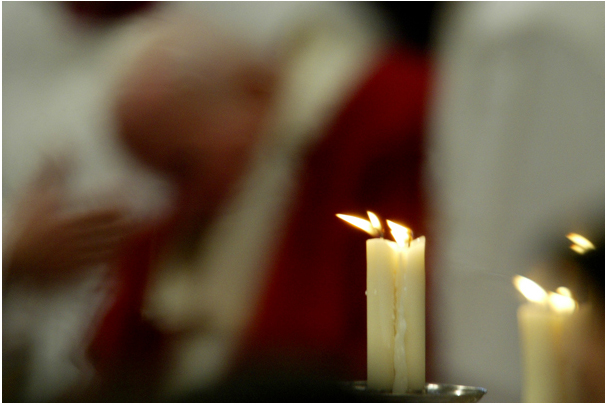 Candles burn as Pope John Paul II leads a mass inside Saint Peter's Basilica at the Vatican November 13, 2003. The Pope and senior cardinals prayed on Thursday for the victims of the attack which killed 18 Italians when suicide bombers hit a military base in southern Iraq. REUTERS/Giampiero Sposito